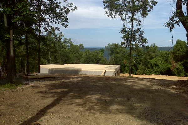 The deck poured over the basement, a flat slab sitting in the trees with the valley dropping away beyond it.