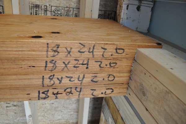 A log marked in carpenter's pencil — 18 x 24 2.0, written twice — one of the numbered pieces waiting to be set.