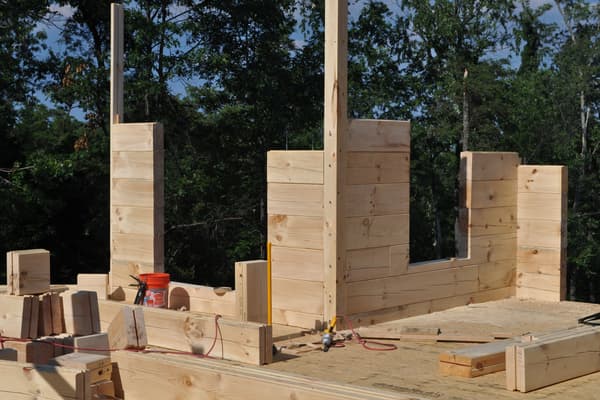 The walls higher, door and window openings framed by the log courses, posts up for the roof to land on.