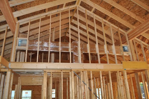 Interior framing under the cathedral ceiling, a loft opening and stud walls dividing up the log shell.