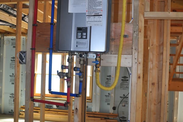 The mechanical wall — a tankless water heater and the manifold, with plumbing lines run out through the studs.