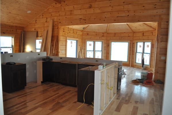 The kitchen in, dark cabinets and wood floor, the curved wall of the round room and its windows beyond.