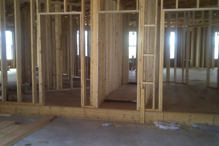 The interior in stud framing, ceiling joists overhead and door openings running through to daylight at the far wall