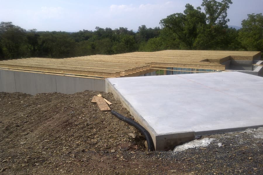 The subfloor decked over the foundation, a concrete slab poured alongside, spoil banked around the edges