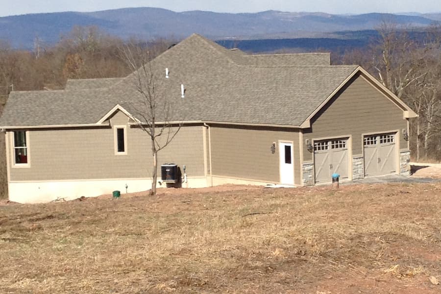 The house and garage wing seen along the slope, mountains ranged along the horizon behind