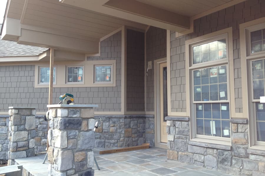 The porch mid-build, stone piers up and a column set, flagstone laid in part across the deck