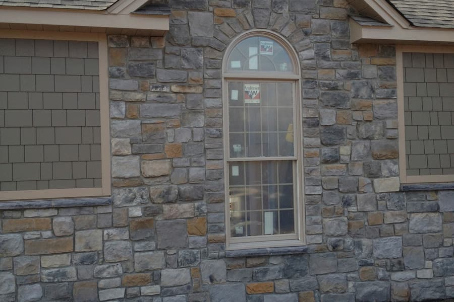 A stone gable end with an arched window, the stonework run right up under the eaves