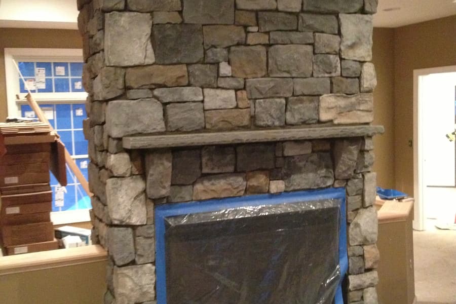 The fireplace part built, stone laid to the ceiling and the firebox opening still masked with plastic